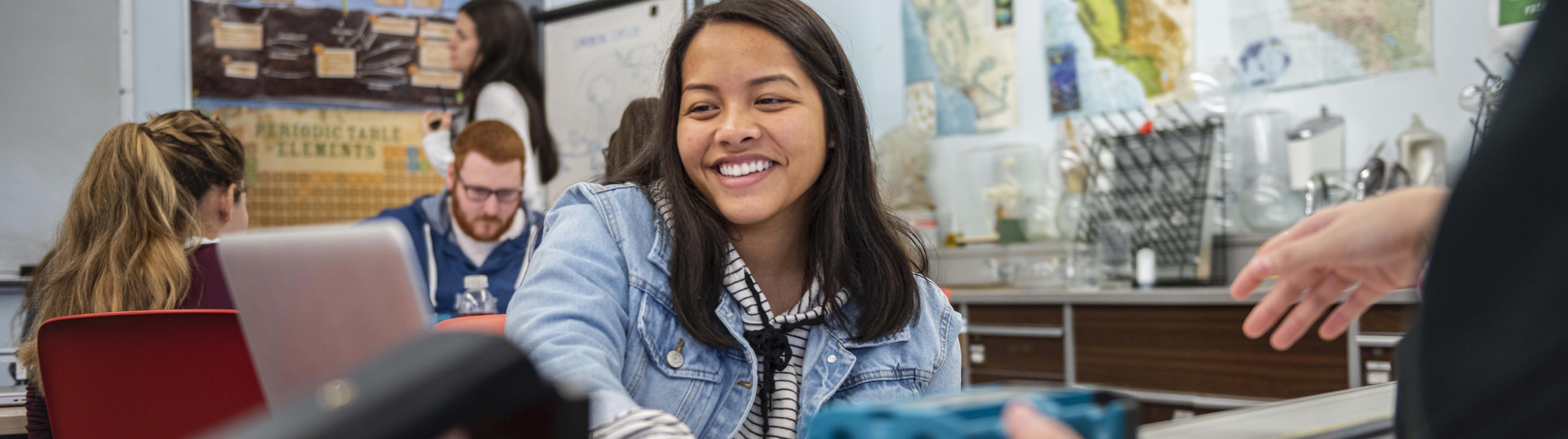 A student smiles during a discussion in a classroom.